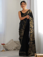 Woman holding a black and gold saree against a white background