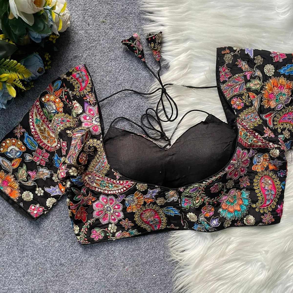 Black bikini with colorful floral embroidery on a textured surface