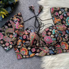 Colorful embroidered top on a textured surface with floral decorations in the background