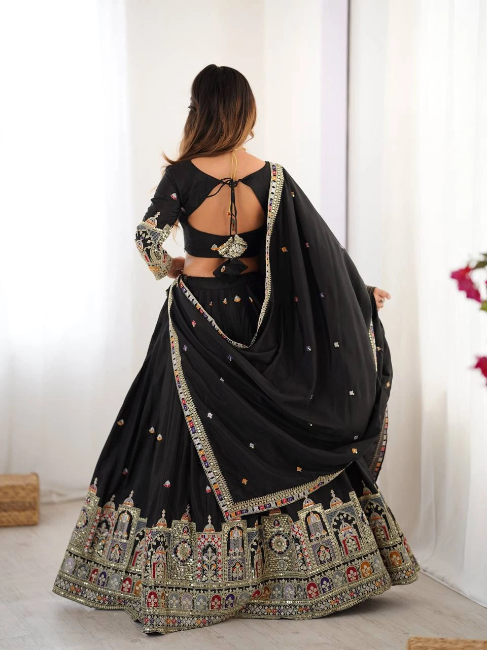 Black embroidered traditional outfit with a white curtain background