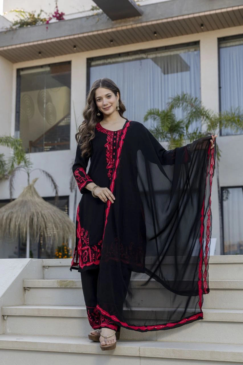 Woman in a black and red traditional outfit standing on steps outdoors.