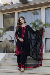 Woman in a black and red traditional outfit standing on steps outdoors.