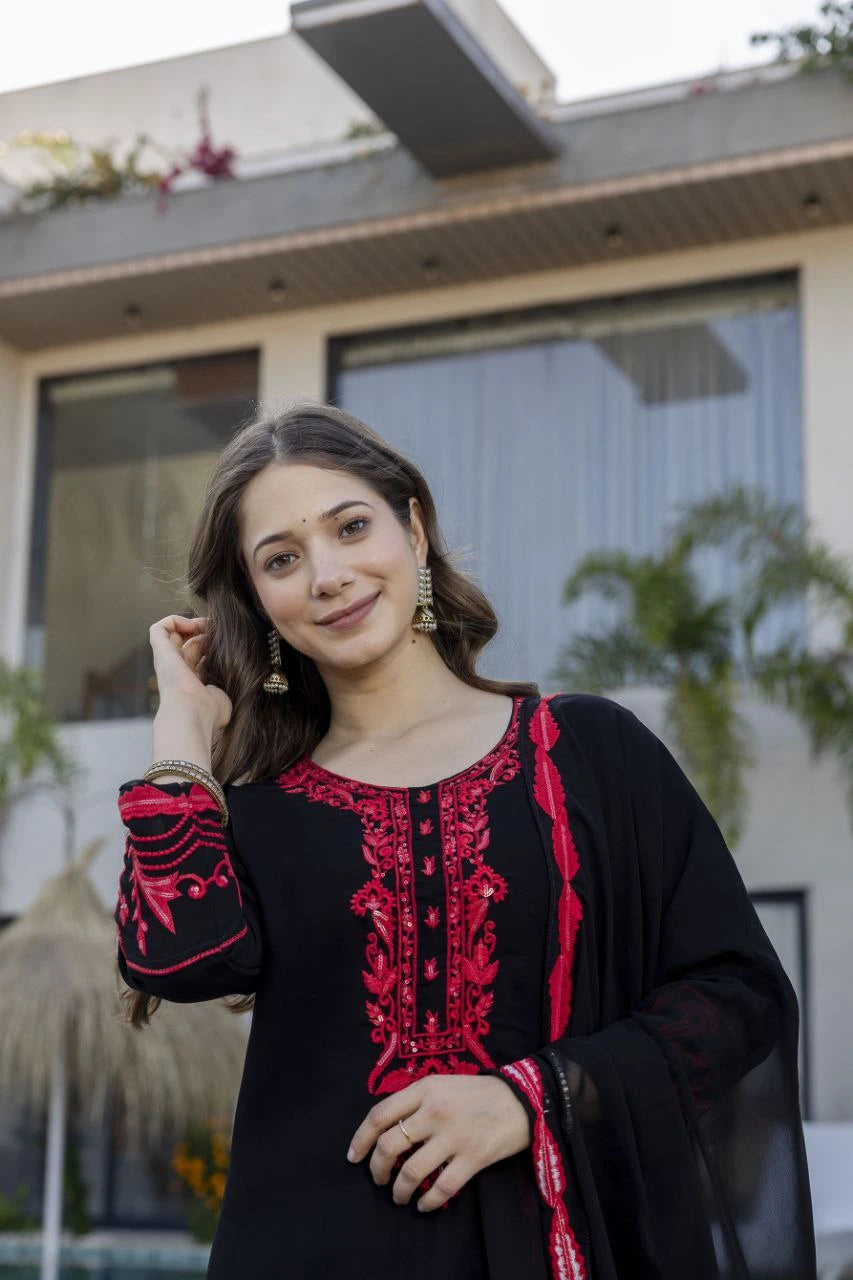 Woman wearing a black and red embroidered traditional outfit outdoors.