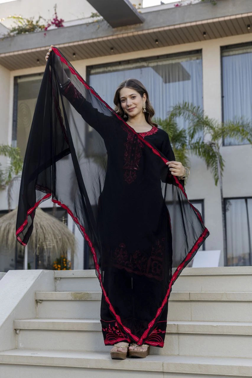 Woman holding a black and red saree in front of a building