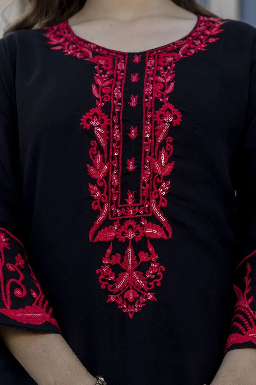 Black top with red intricate embroidery on a blurred background