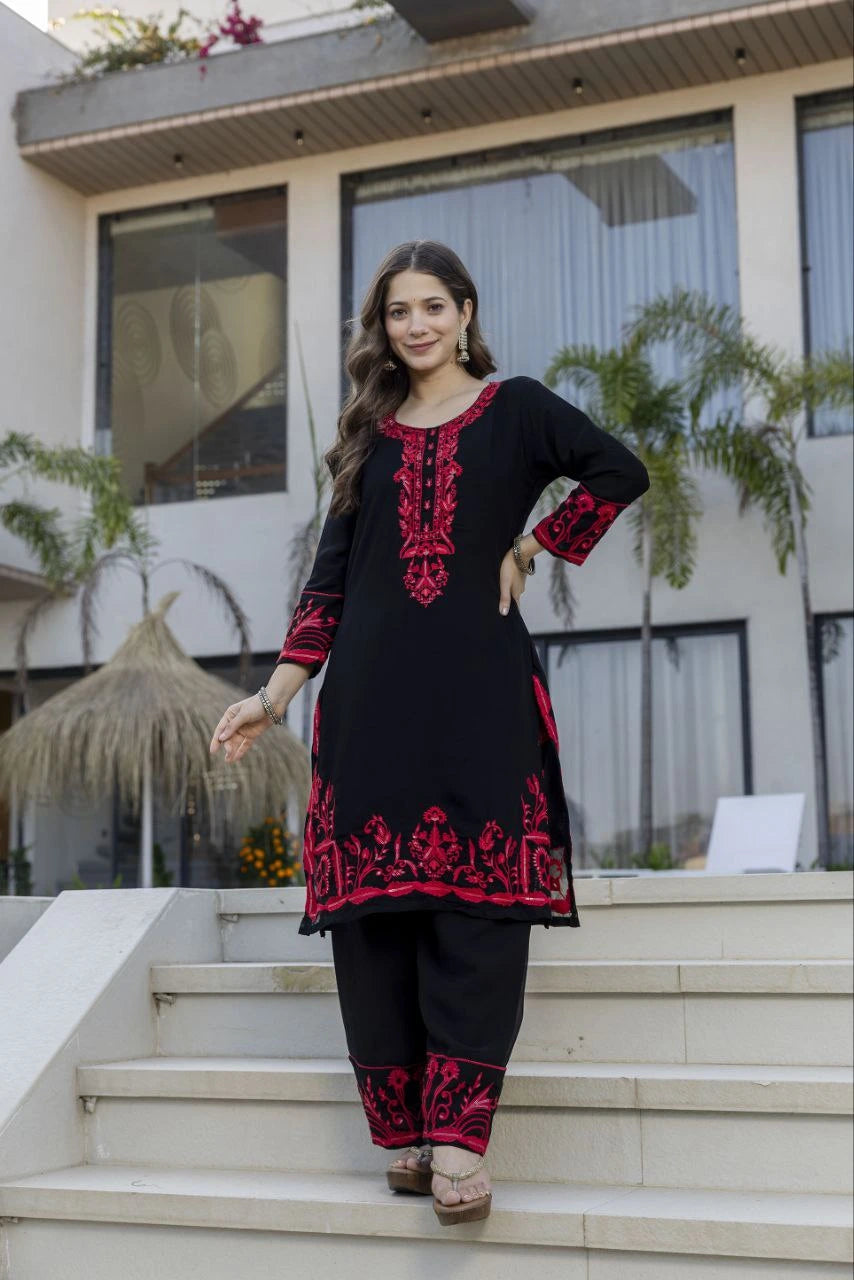 Woman in a black and red traditional outfit standing on steps outside a modern building.
