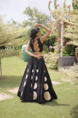 Eye-catching golden circular foil patterns add a bold and fashionable touch to the flowing black skirt.