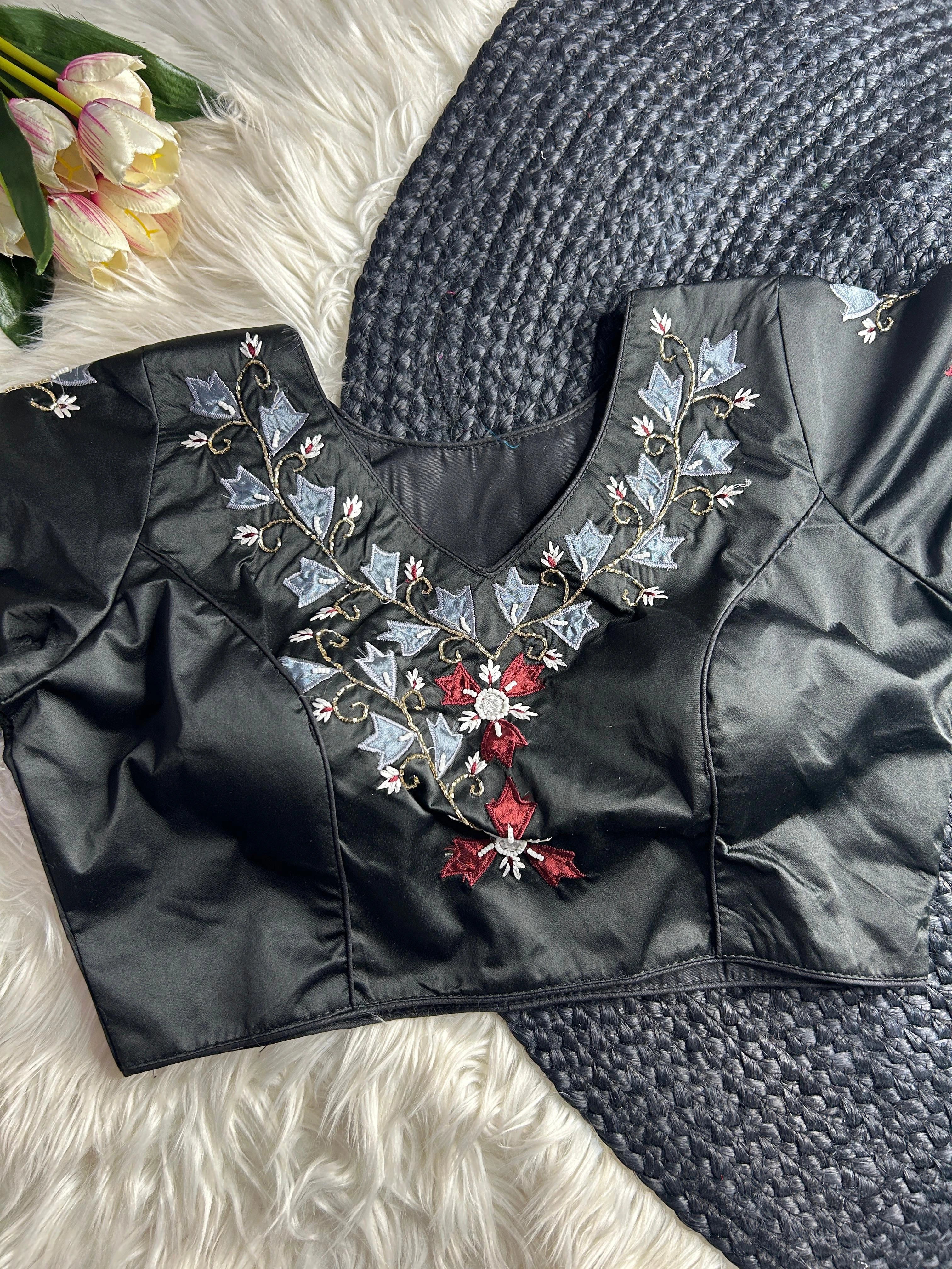 Black blouse with floral embroidery on a textured surface