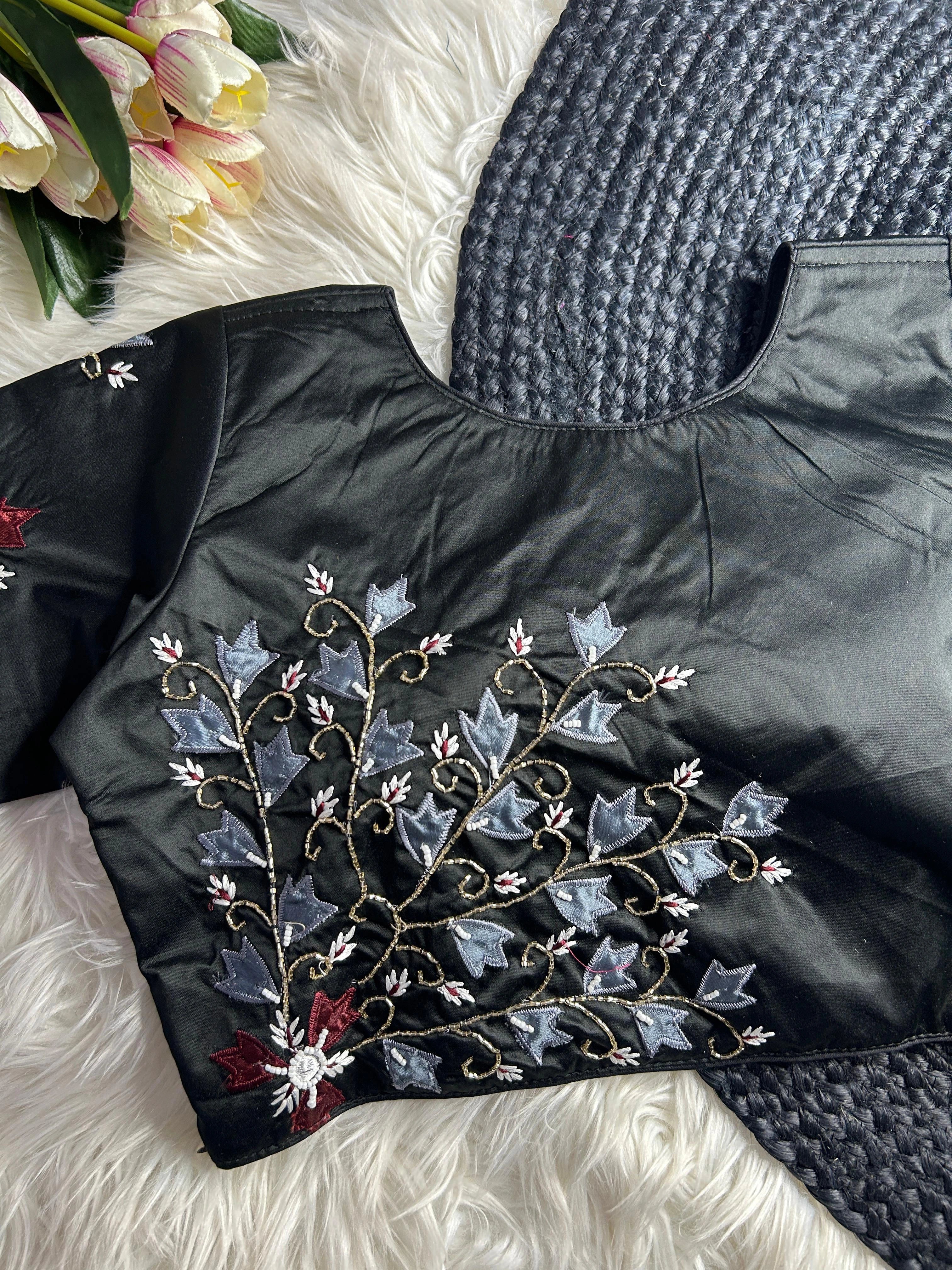 Black jacket with floral embroidery on a textured surface with flowers in the background