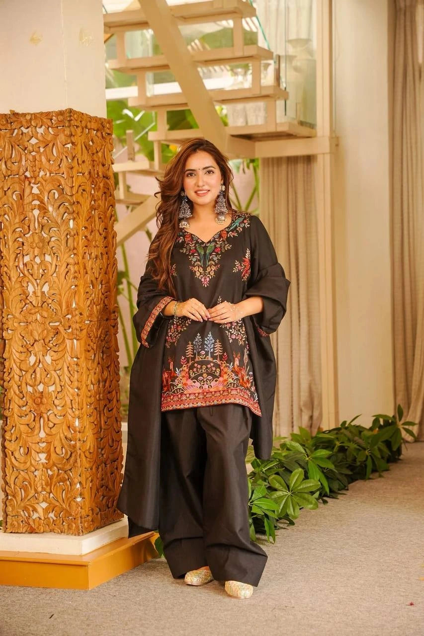 Woman in traditional outfit standing in a decorated indoor setting with wooden columns and plants.