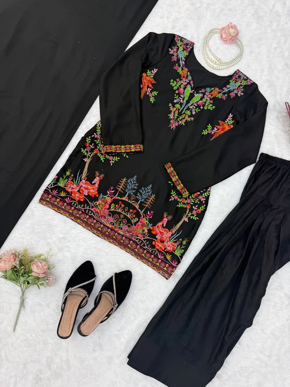 Black outfit with colorful floral embroidery on a white background