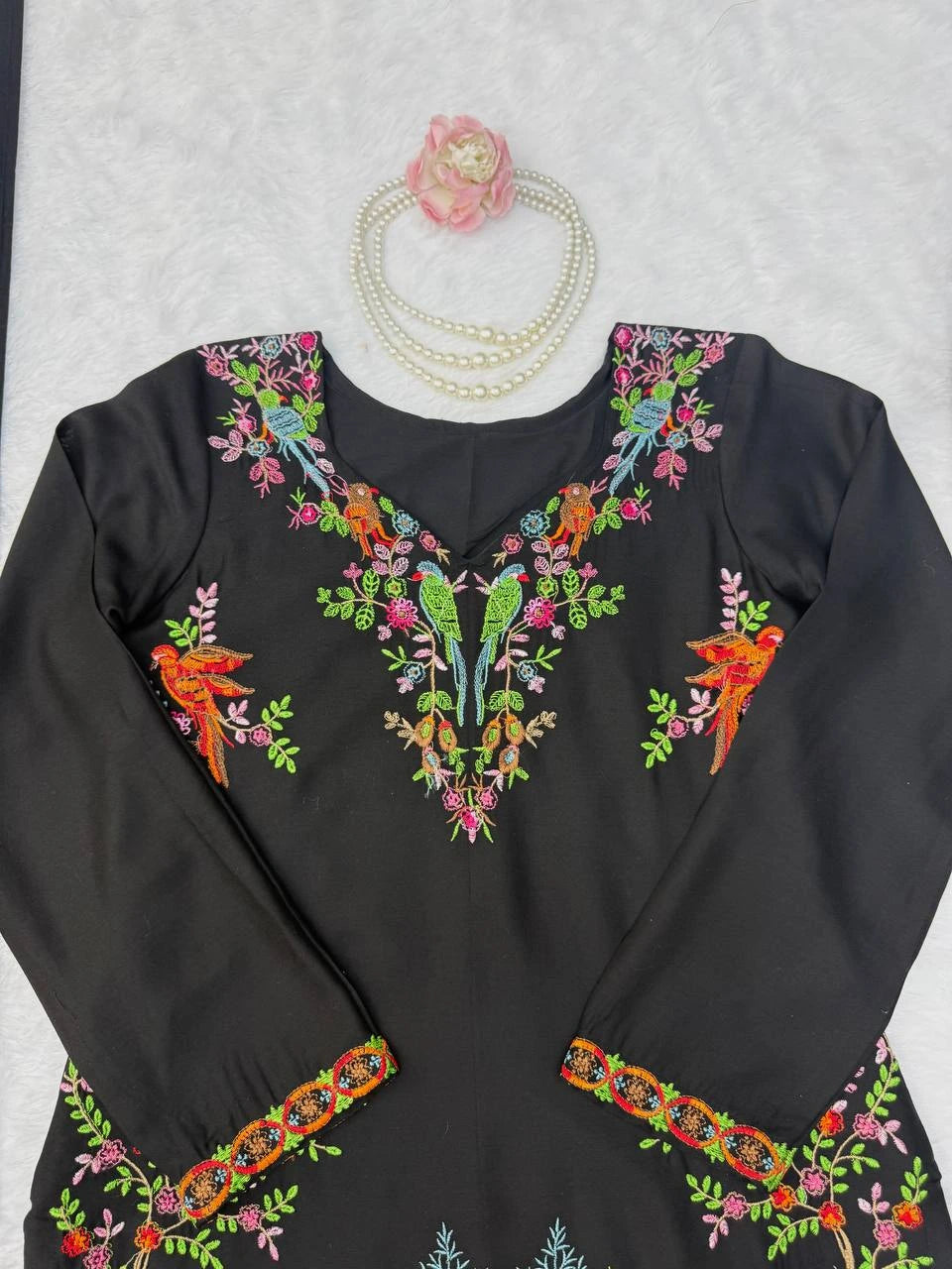 Black long-sleeve top with colorful embroidery on a light gray background