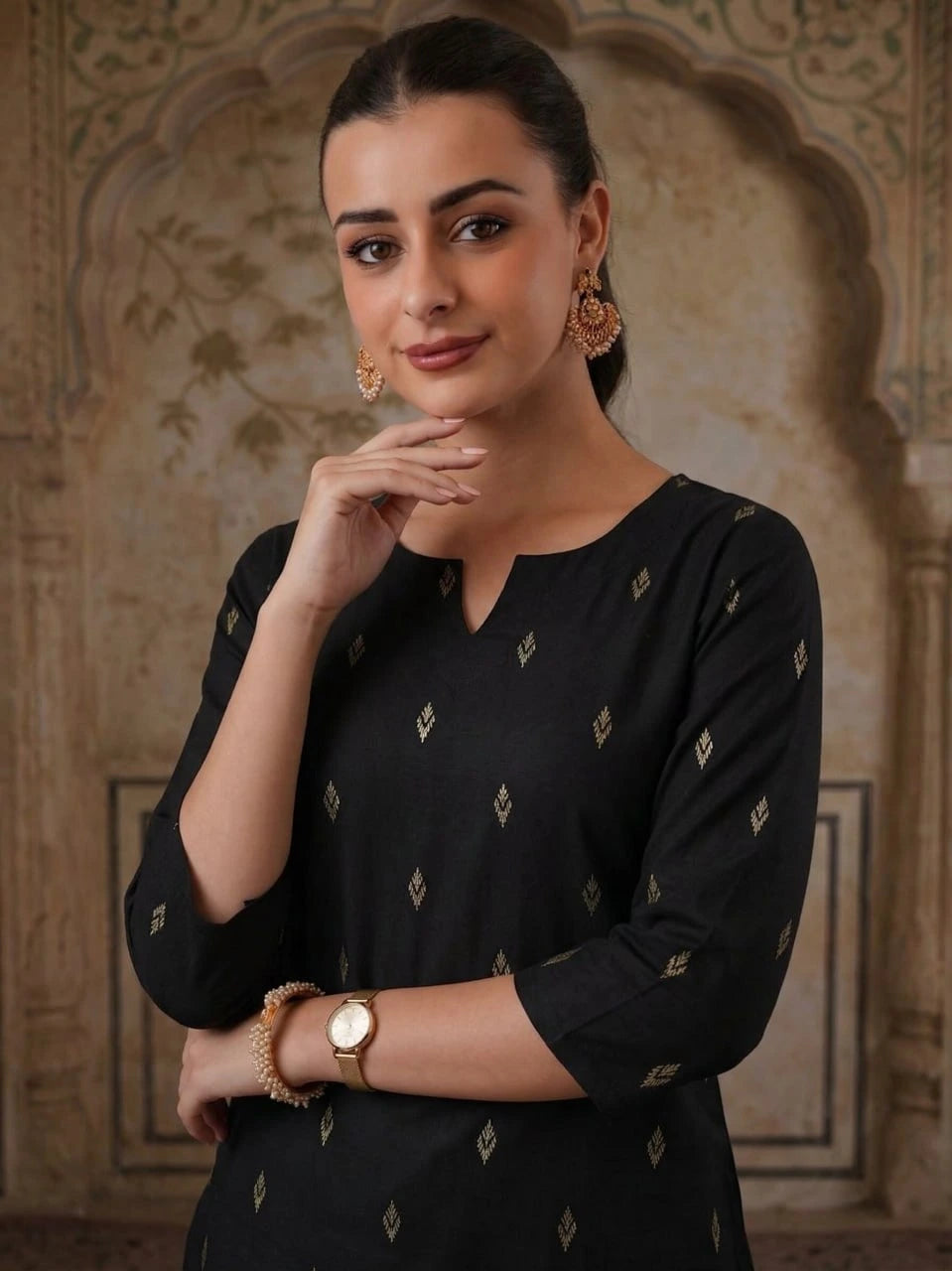 Woman wearing a black traditional outfit with gold patterns in an ornate setting