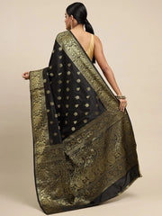 Woman wearing a black saree with gold patterns on a beige background