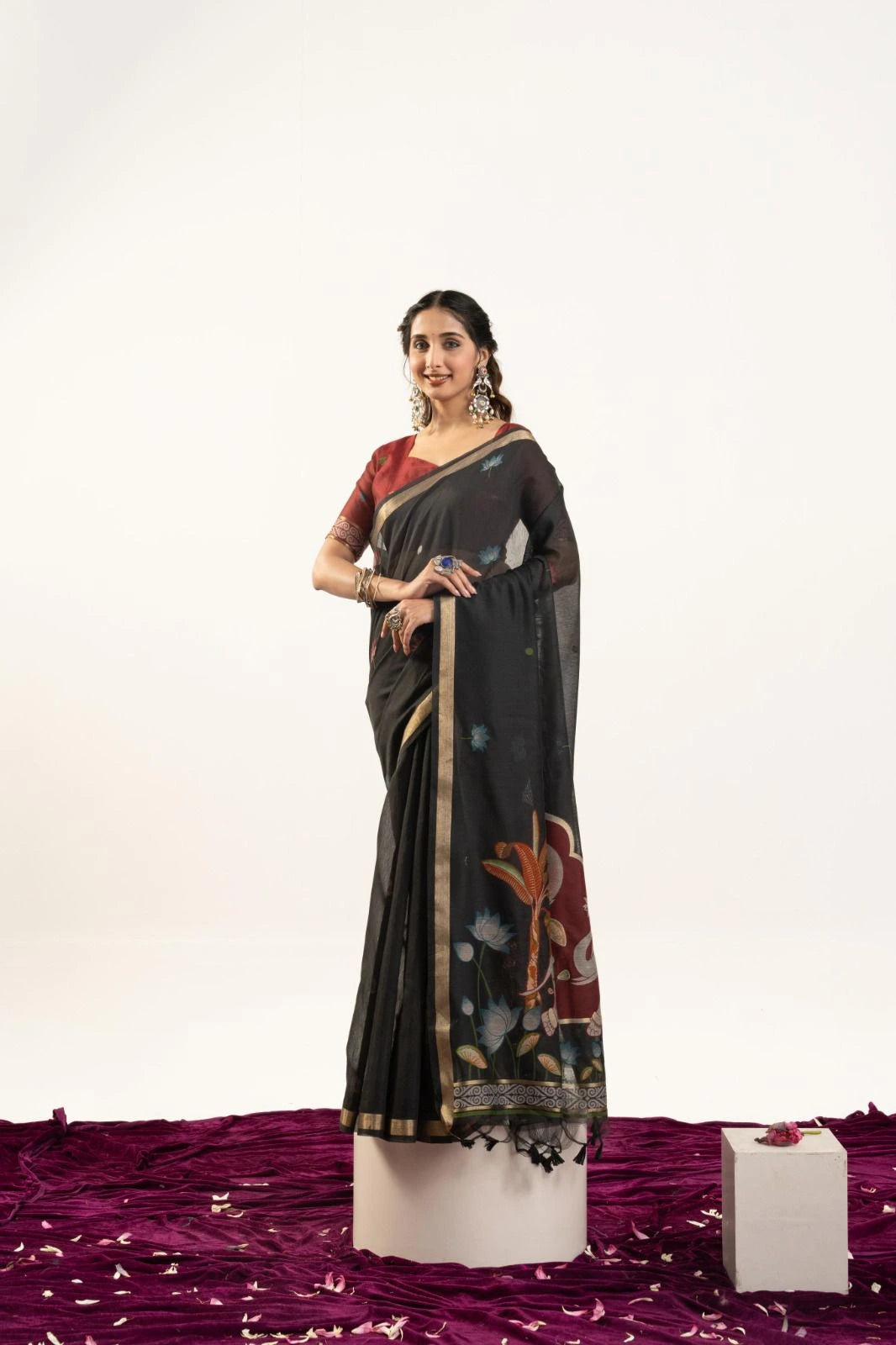 Woman wearing a black saree with floral patterns on a white background