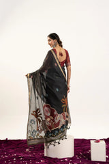 Woman wearing a black saree with floral patterns on a white background