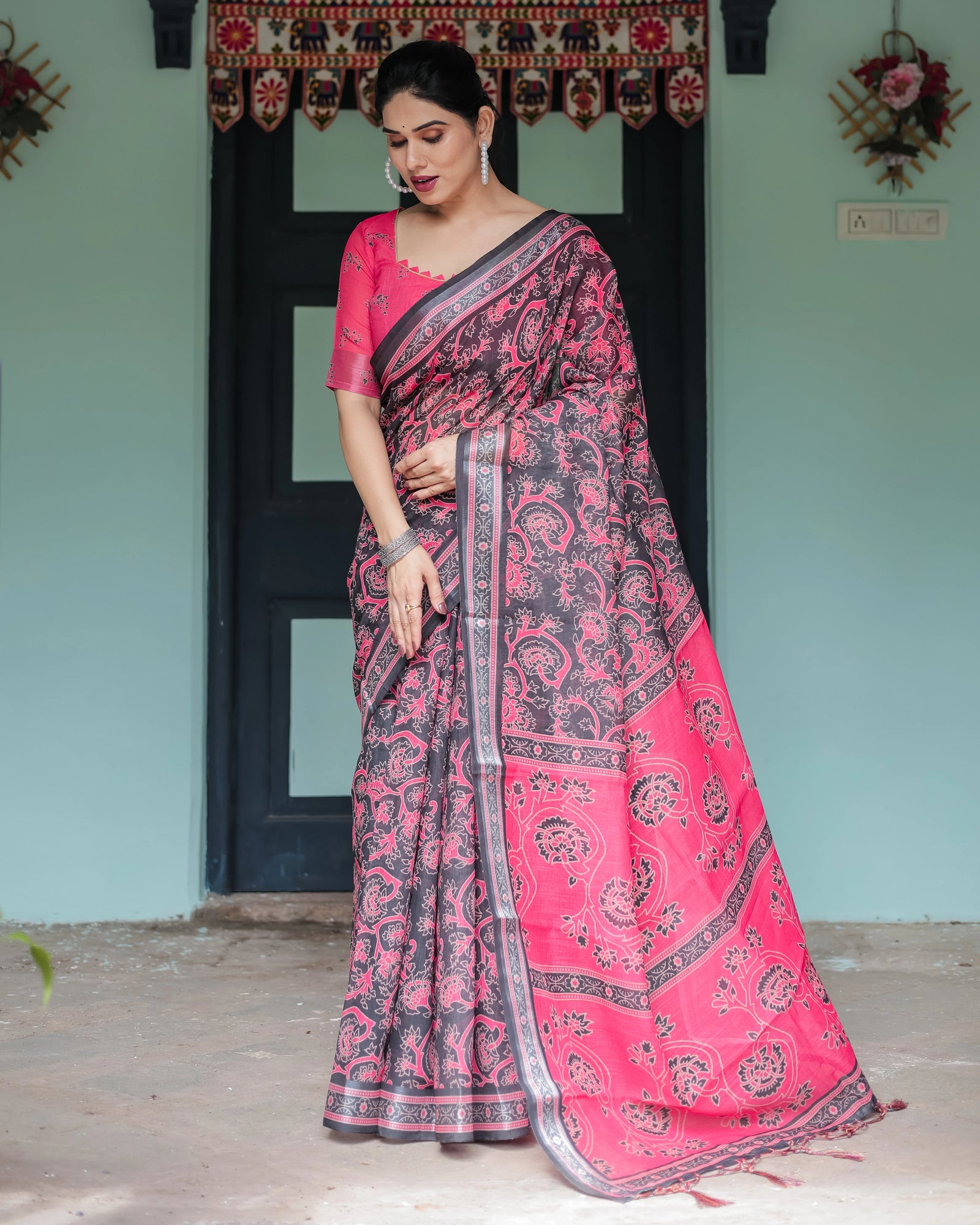 Woman wearing a pink and black saree in an indoor setting