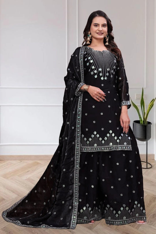Woman wearing a black embroidered traditional outfit with a white background