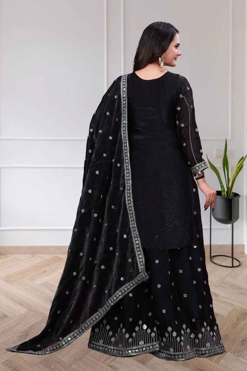 Woman wearing a black traditional outfit with embroidery in a minimal indoor setting