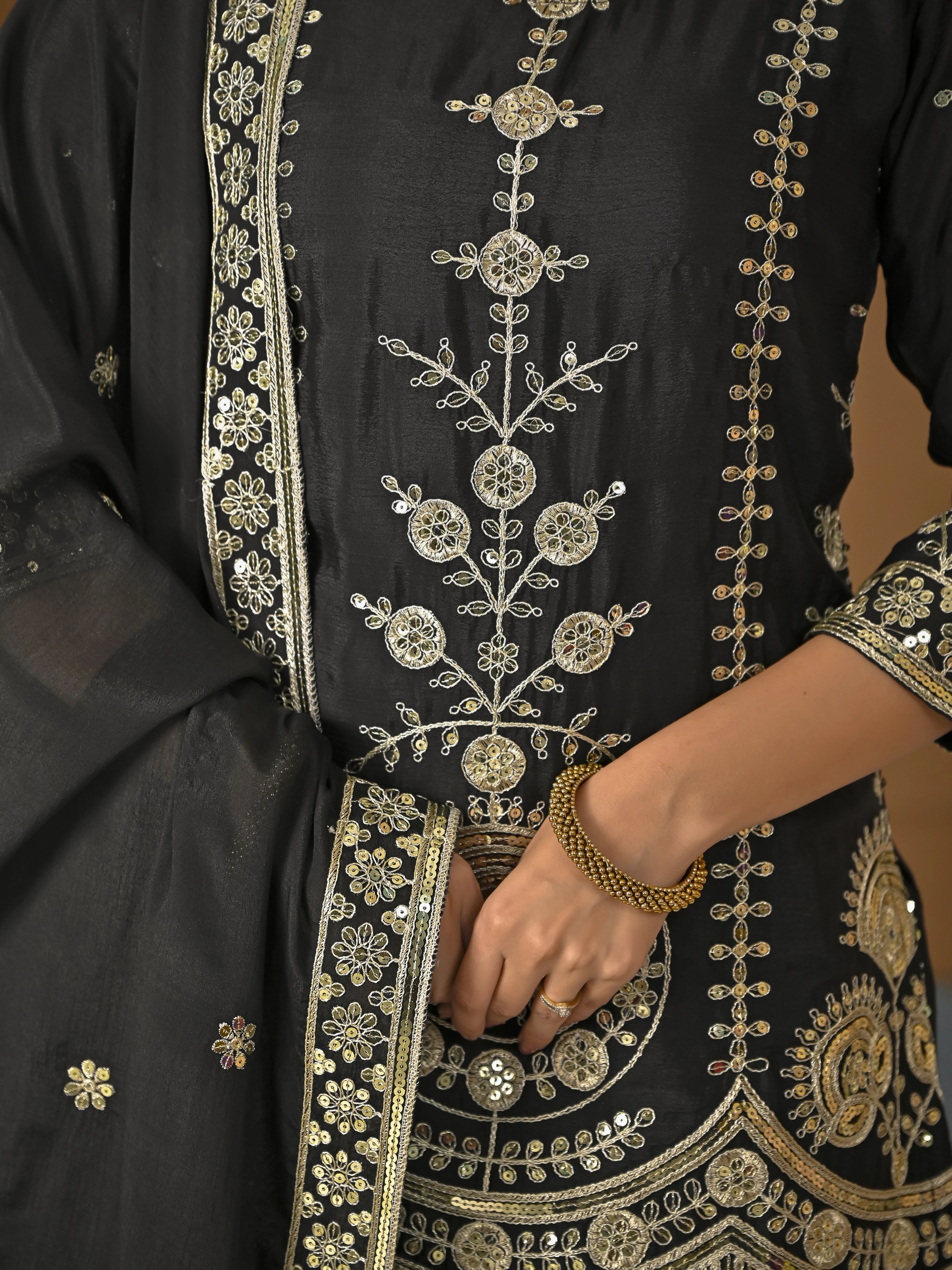 Black outfit with intricate gold embroidery on a plain background