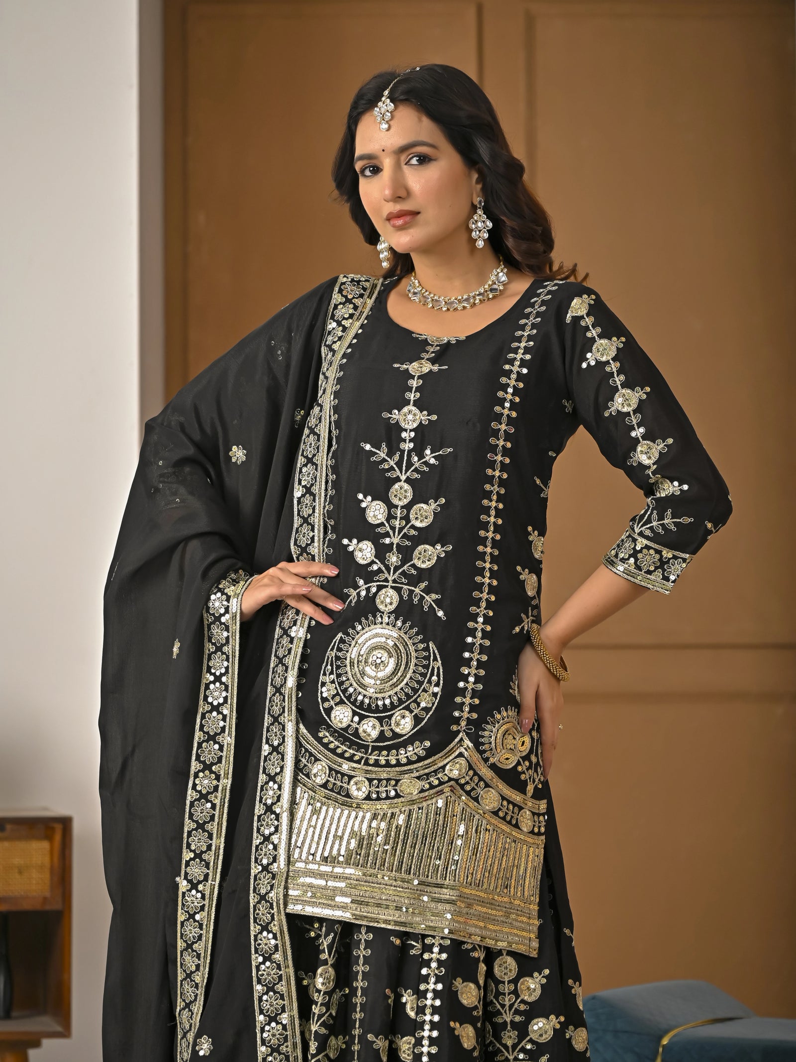 Woman wearing a black embroidered traditional outfit with gold details.