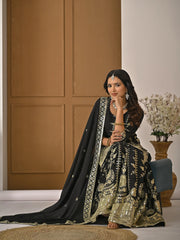 Woman in traditional black and gold outfit sitting on a chair with a neutral background