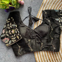 Black embroidered blouse on a textured surface with flowers in the corner