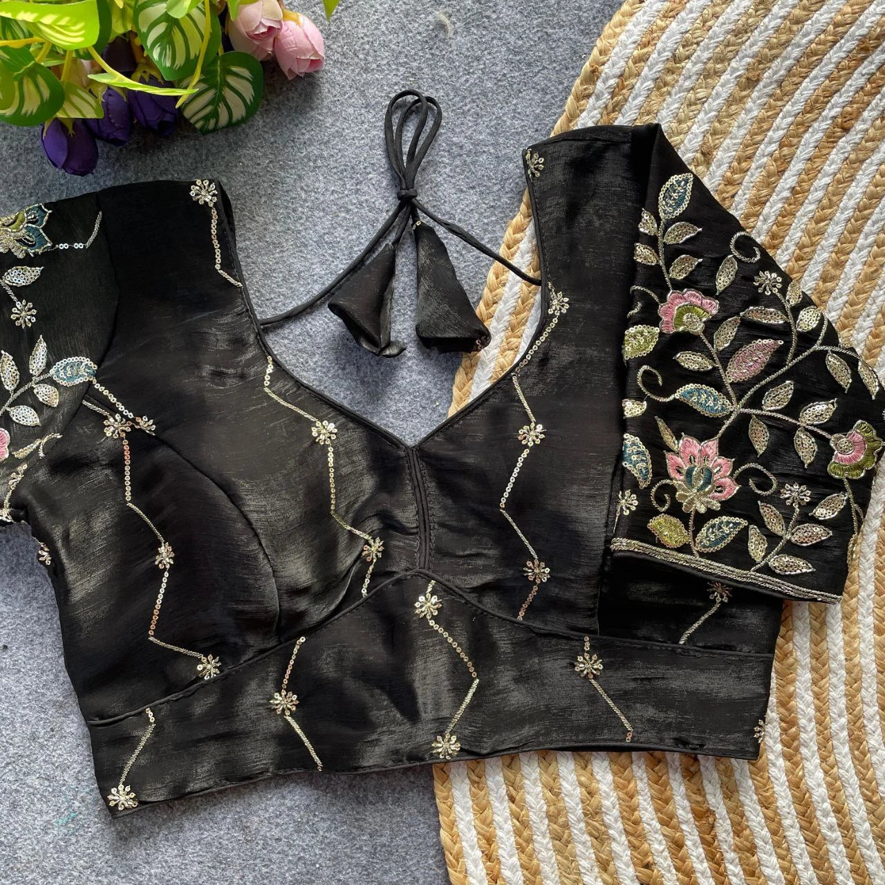 Black embroidered blouse on a textured surface with flowers in the background