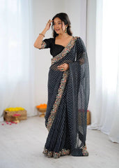 Woman wearing a black saree with gold patterns in a minimalistic setting