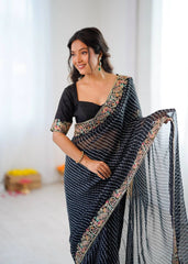 Woman wearing a black saree with a floral blouse against a white background