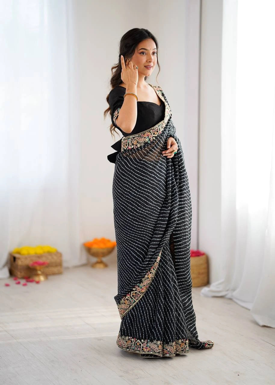 Woman wearing a black saree with gold patterns in a minimalistic setting