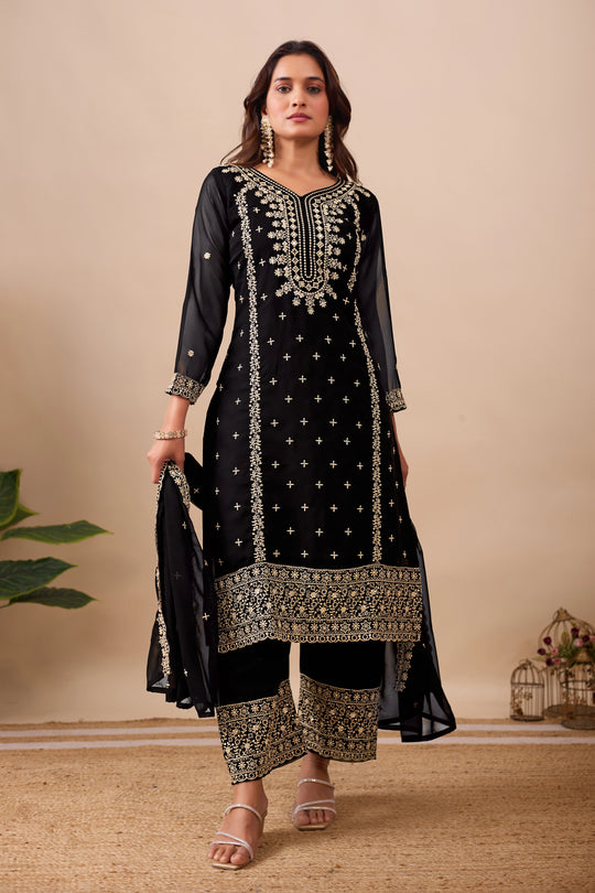 Woman wearing a black embroidered traditional outfit with a beige background