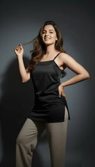 Woman wearing a black top and beige pants against a dark background