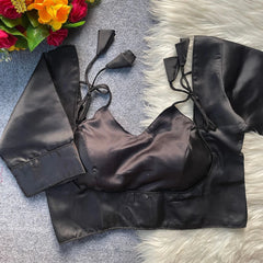 Black satin top with tie straps on a textured surface with flowers in the corner.