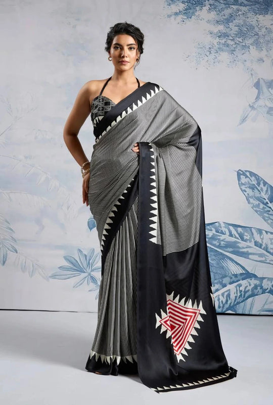 Woman wearing a black and gray saree with white patterns against a light blue floral background