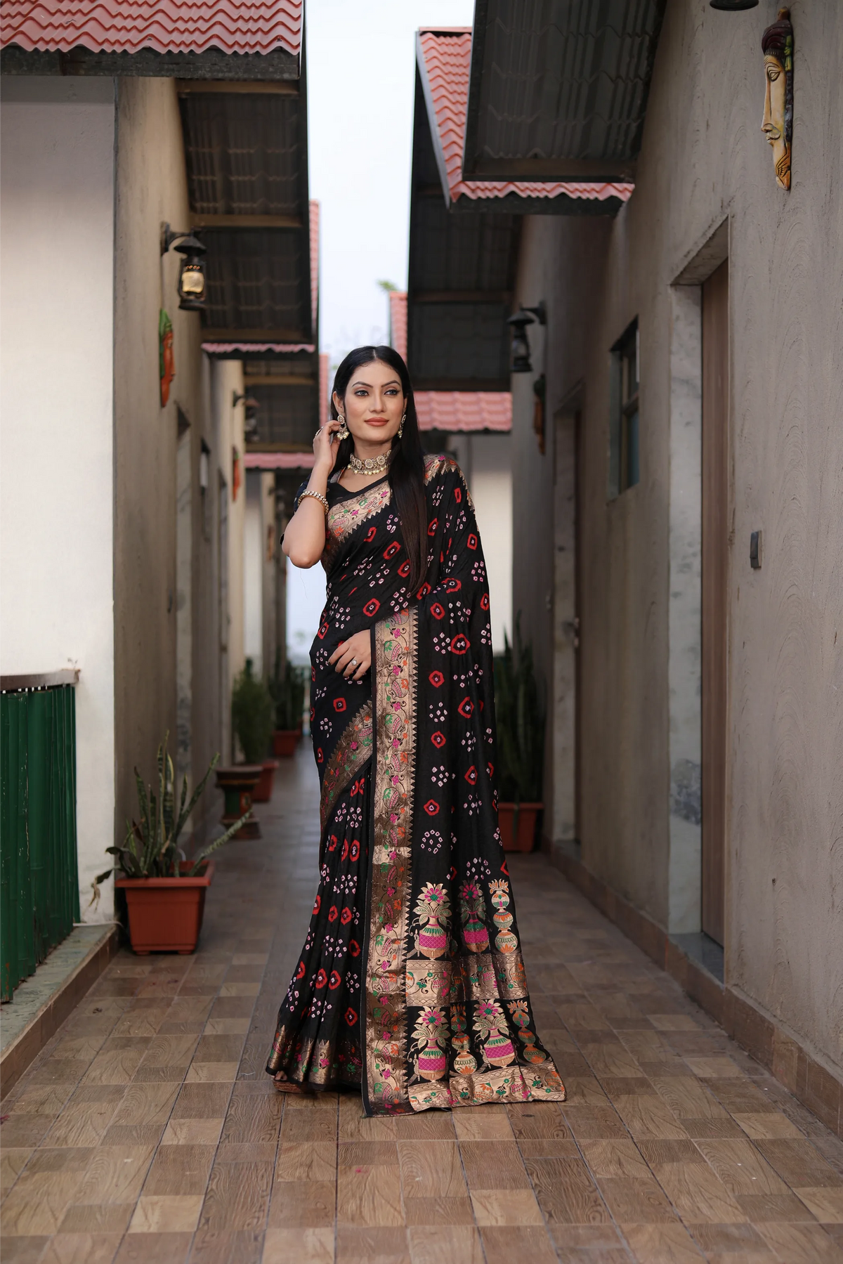 Woman wearing a pink saree with a colorful border outdoors.