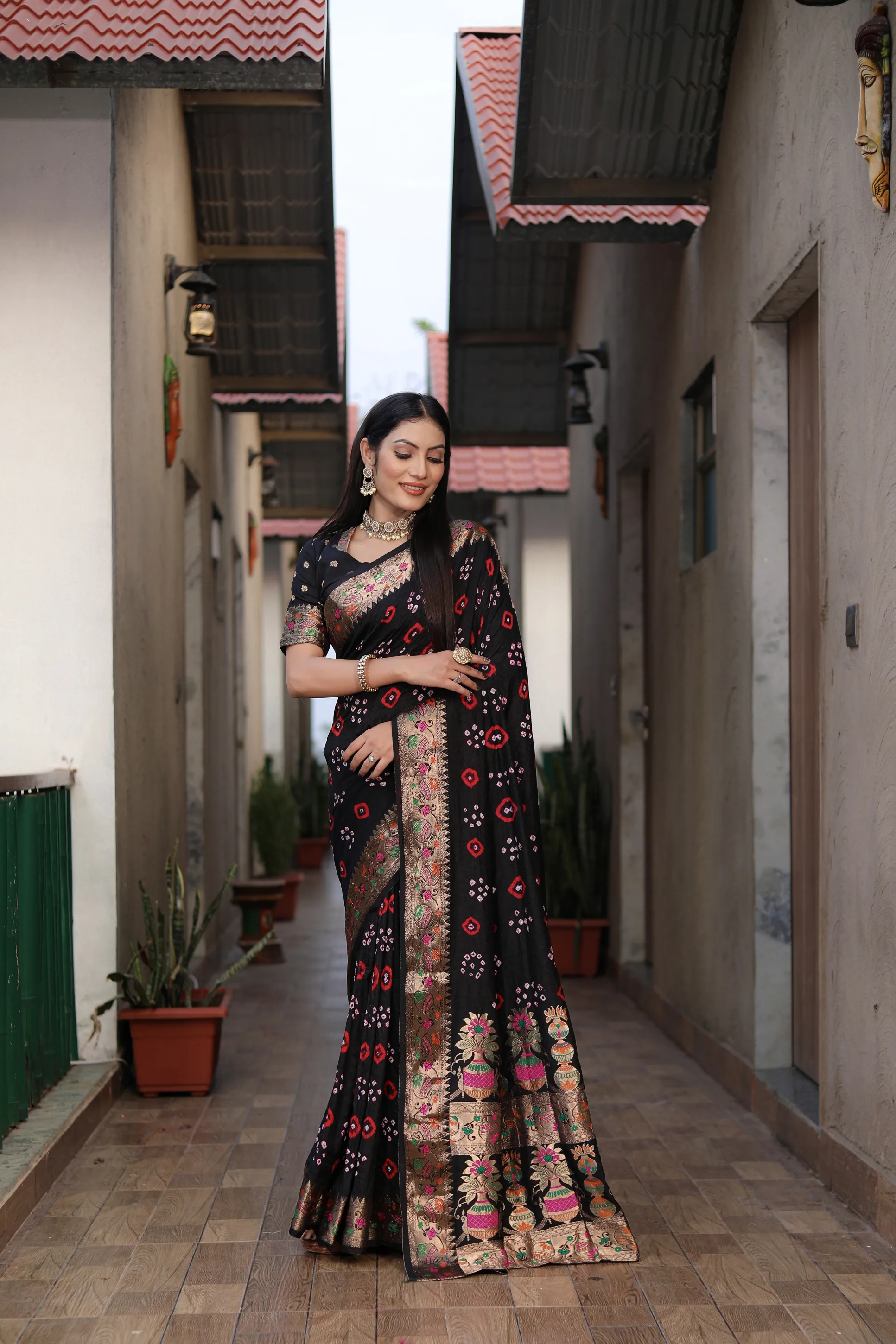 Woman in a traditional saree standing in a narrow alleyway.