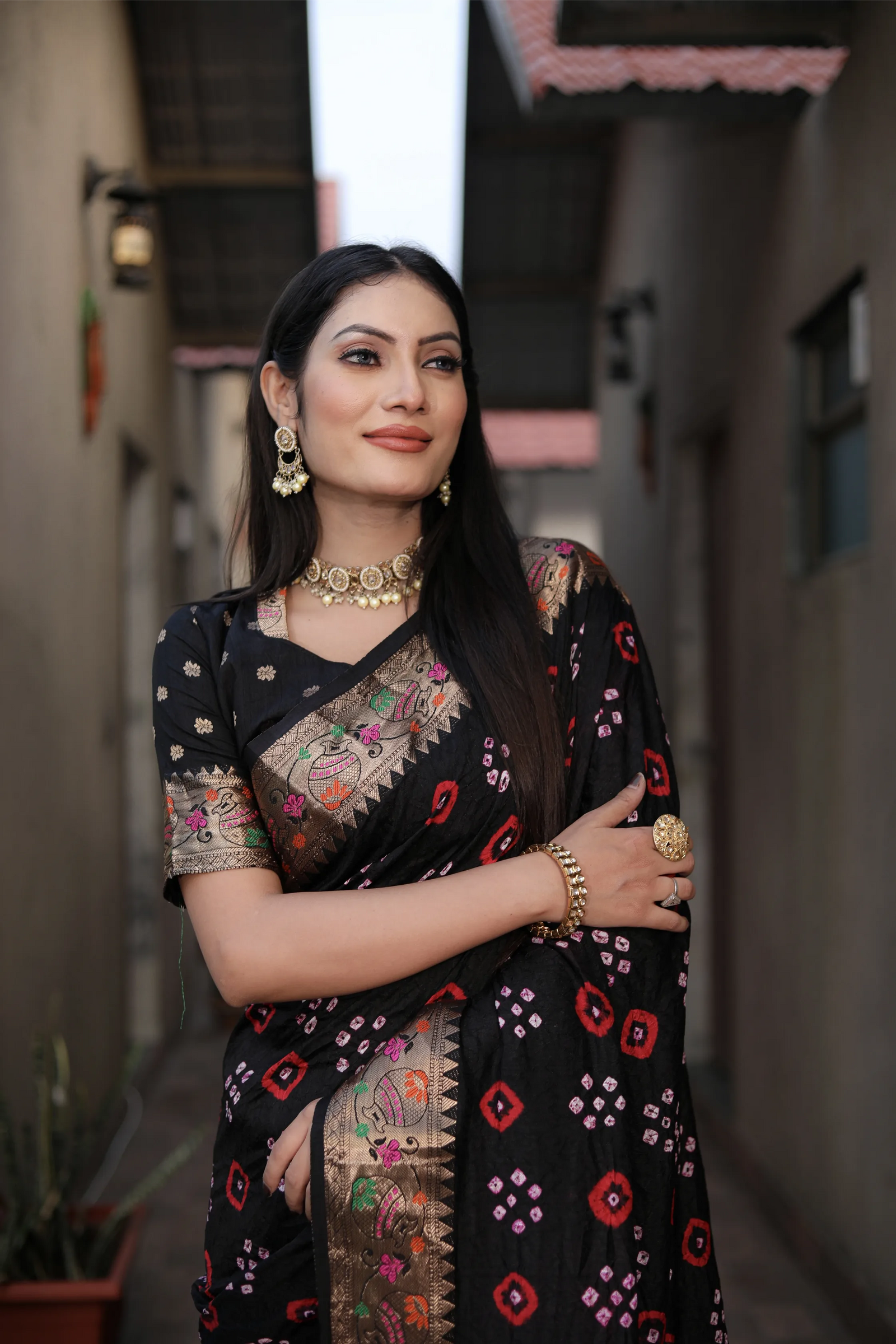 Woman wearing a black saree with floral patterns in an outdoor setting