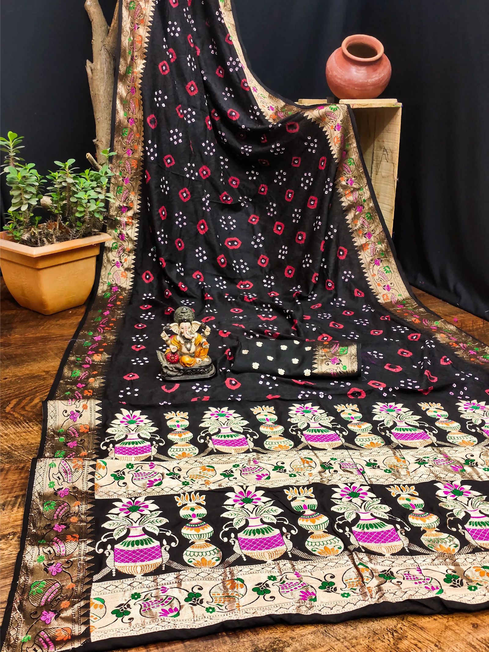 Black floral patterned saree draped over a chair with decorative items on a wooden floor.