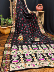 Black floral patterned saree draped over a chair with decorative items on a wooden floor.