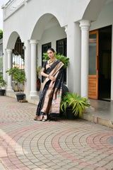 Woman in a traditional saree standing in front of a white building with columns and plants.