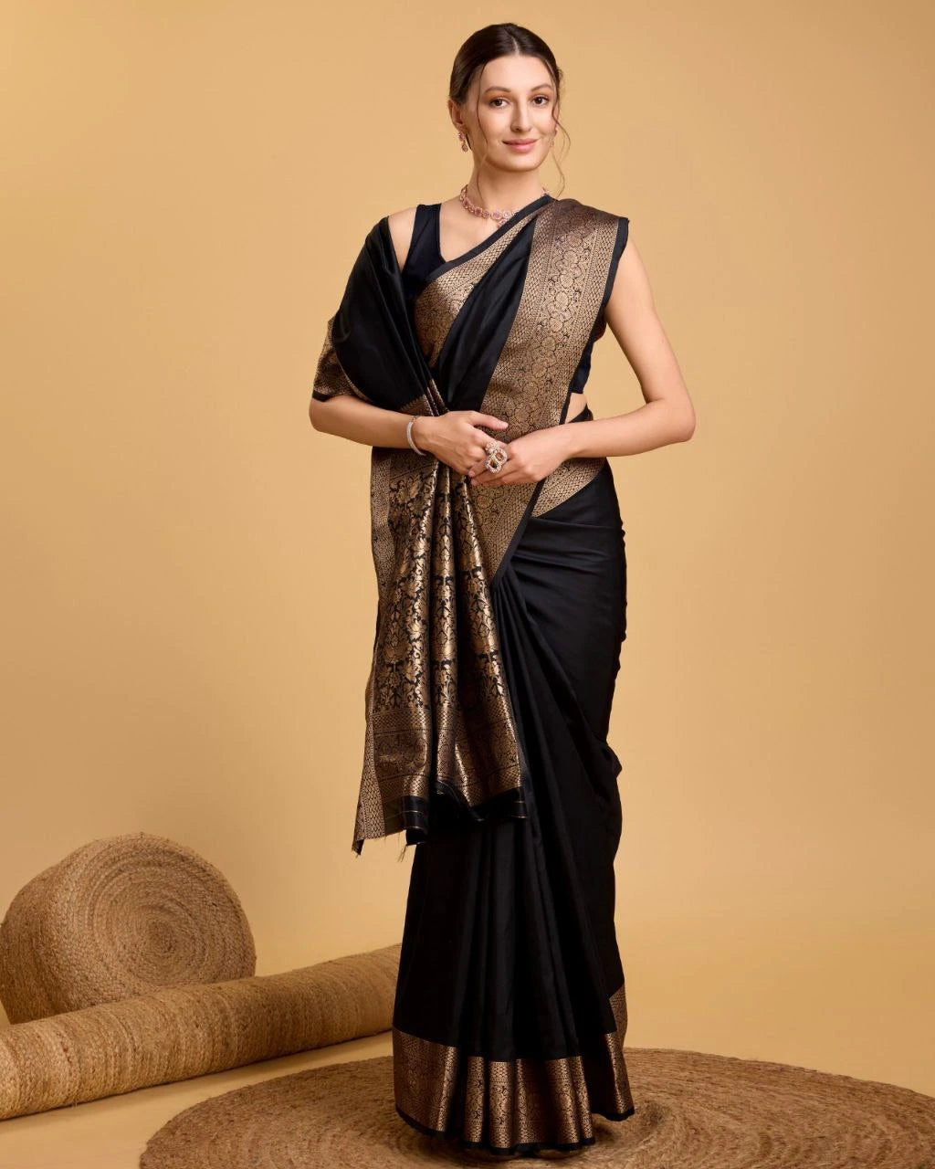 Woman wearing a black saree with gold patterns on a beige background