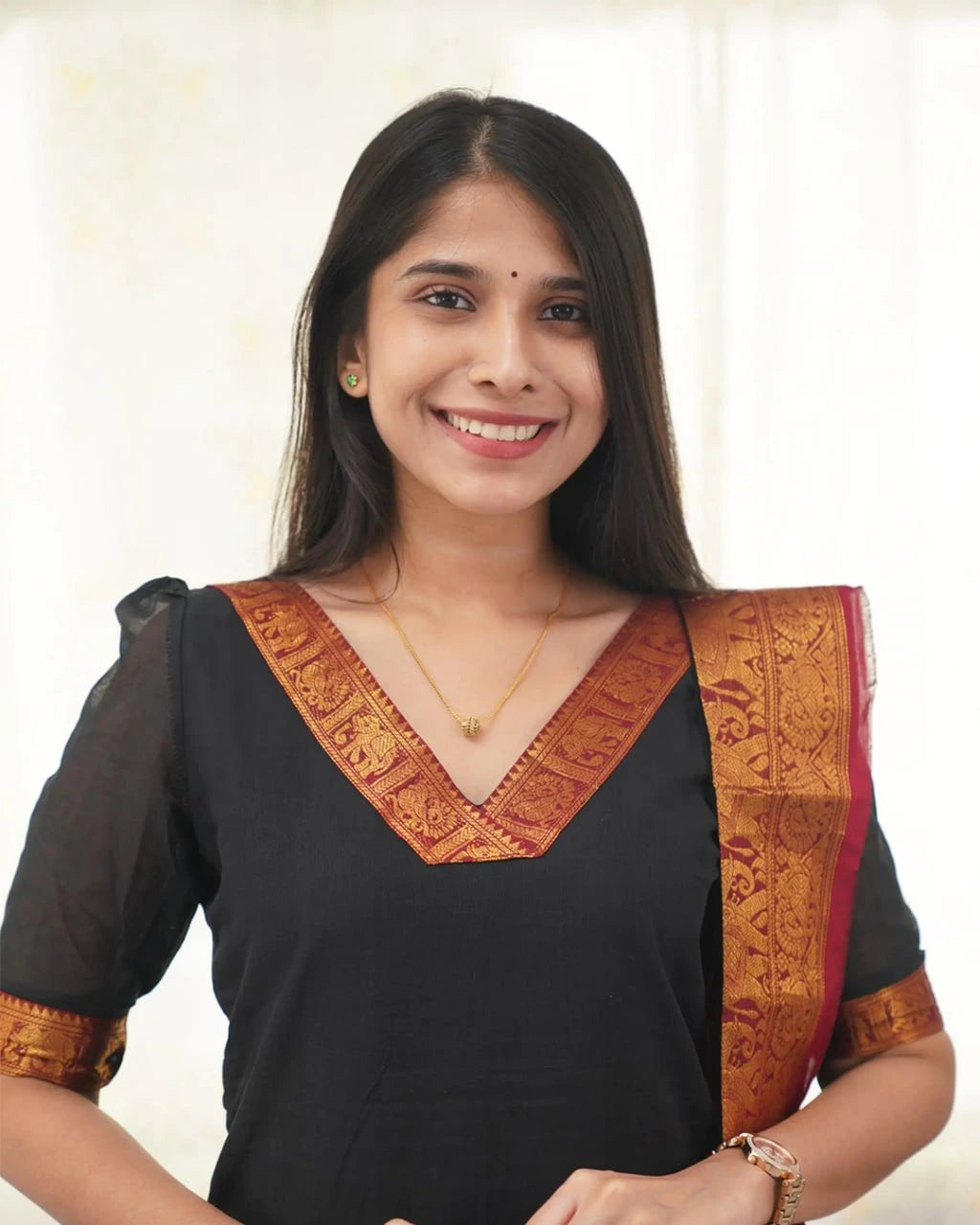 Woman wearing a traditional black and gold saree with a plain background