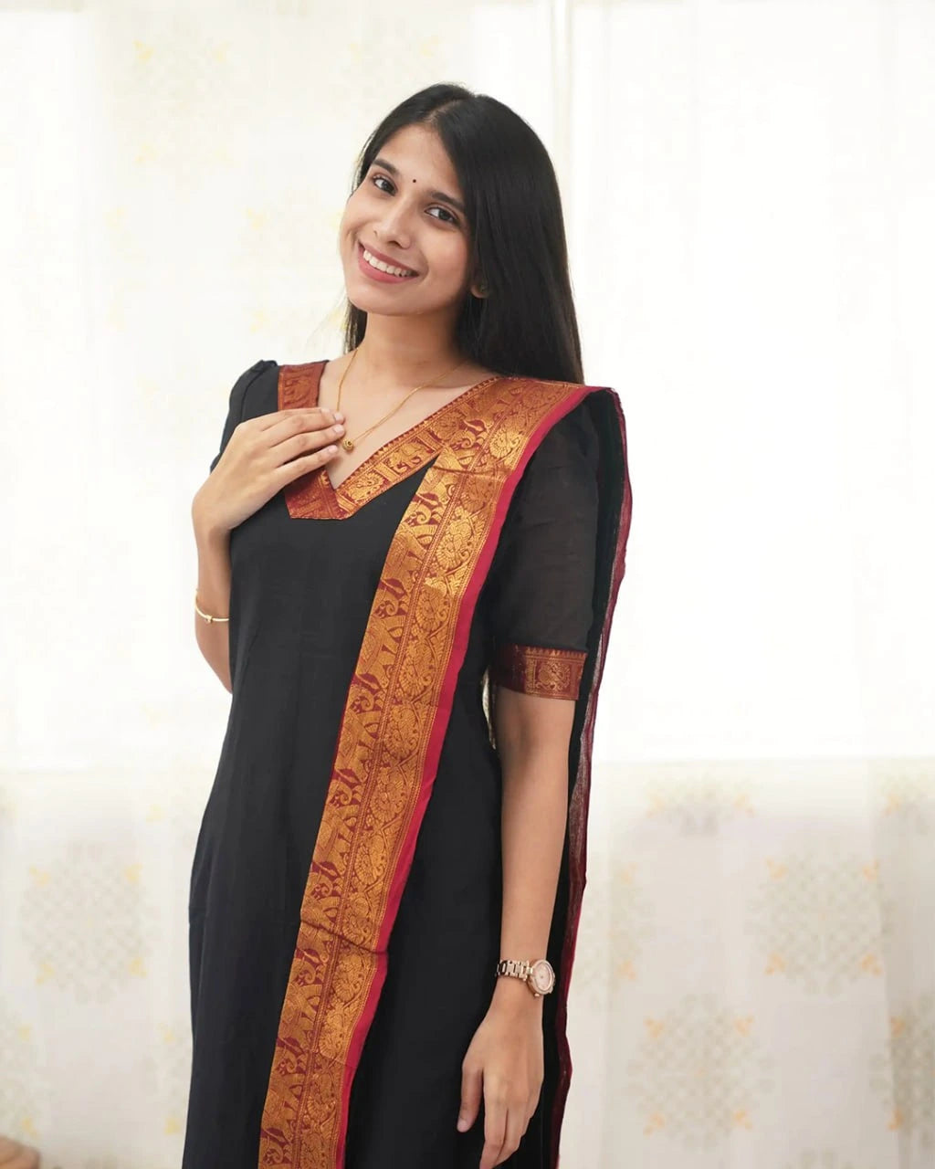 Woman wearing a black saree with a gold border on a white background