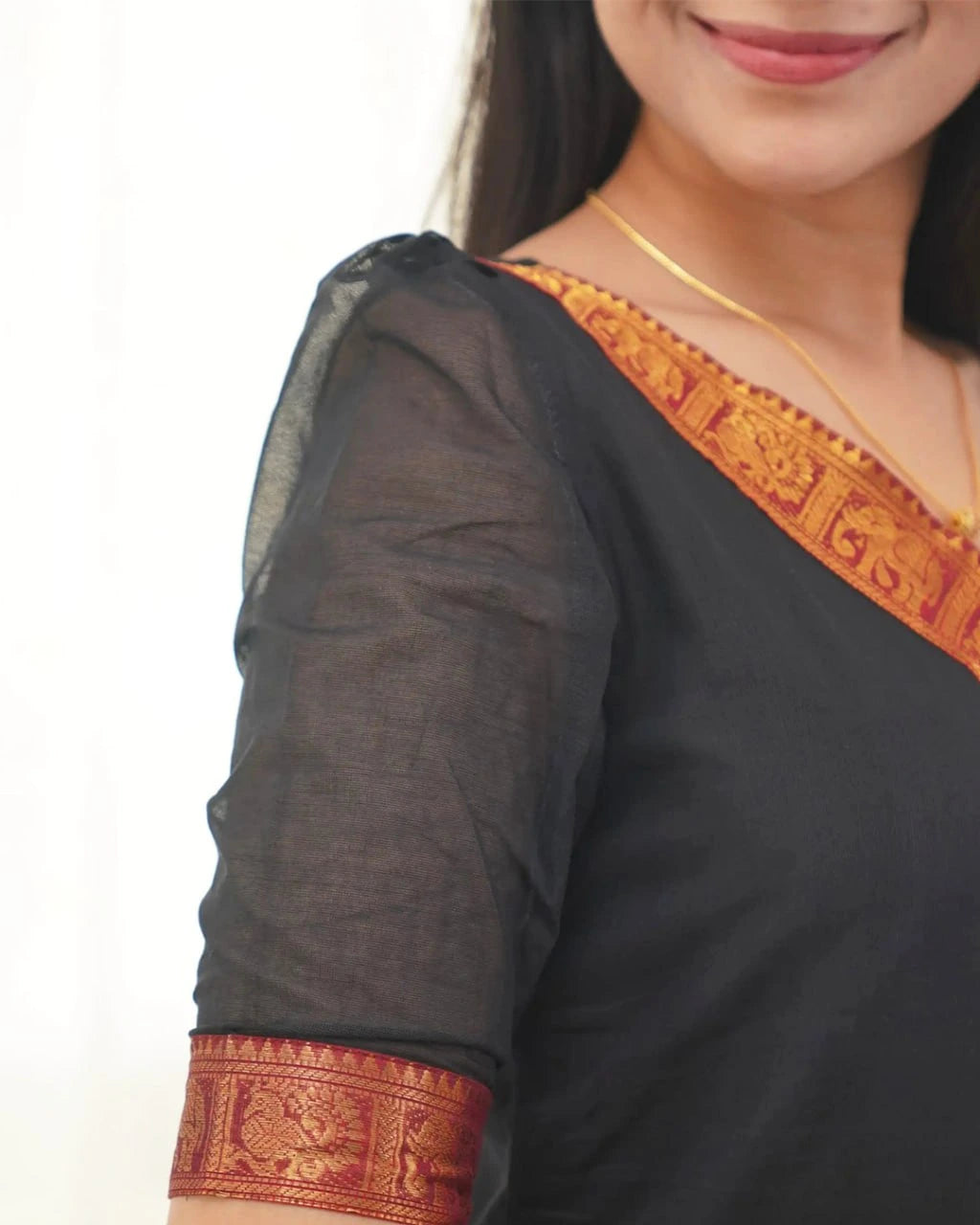Black saree with orange and red border worn by a person
