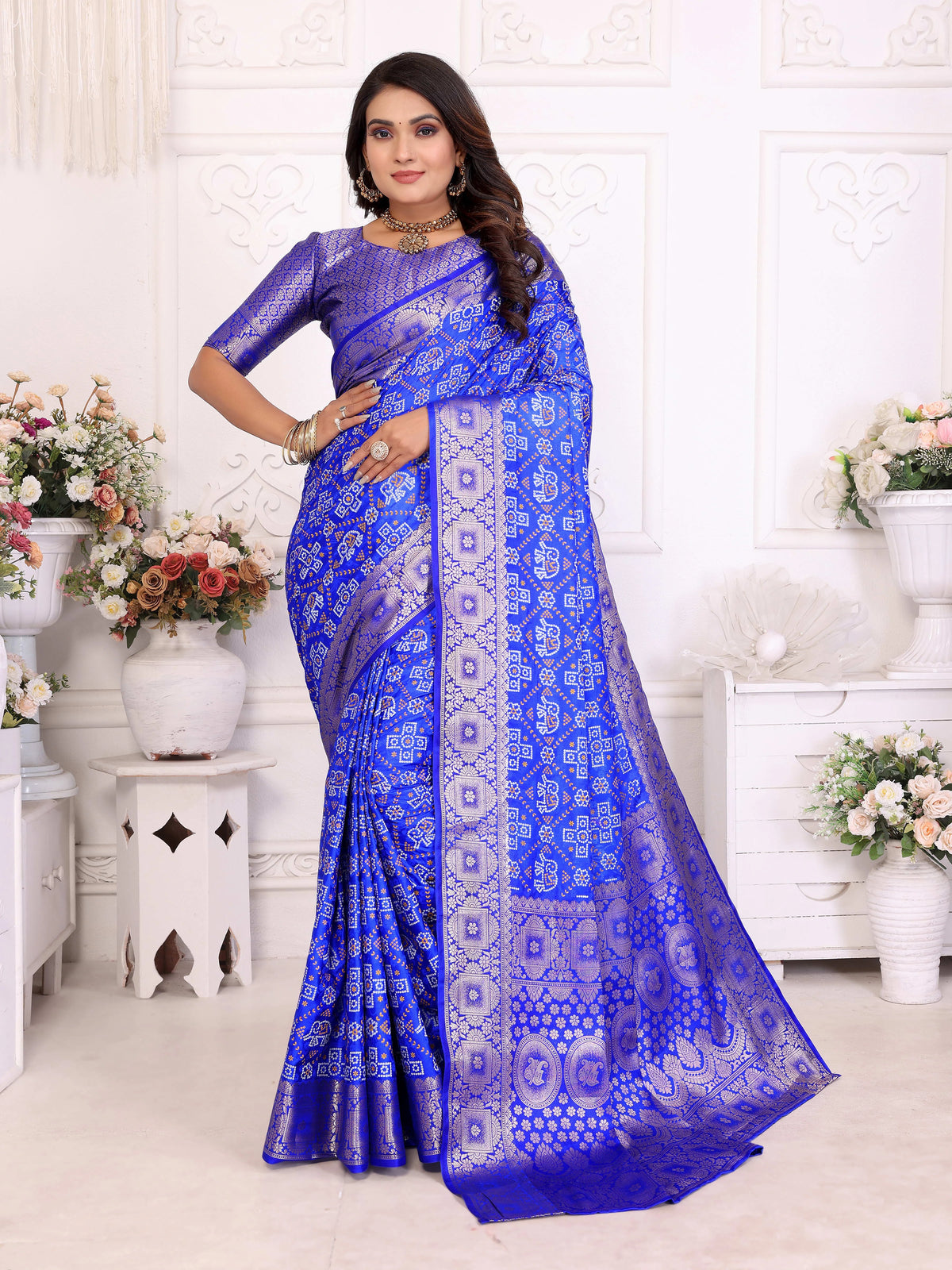 Woman wearing a blue saree with a white pattern in a decorated room.