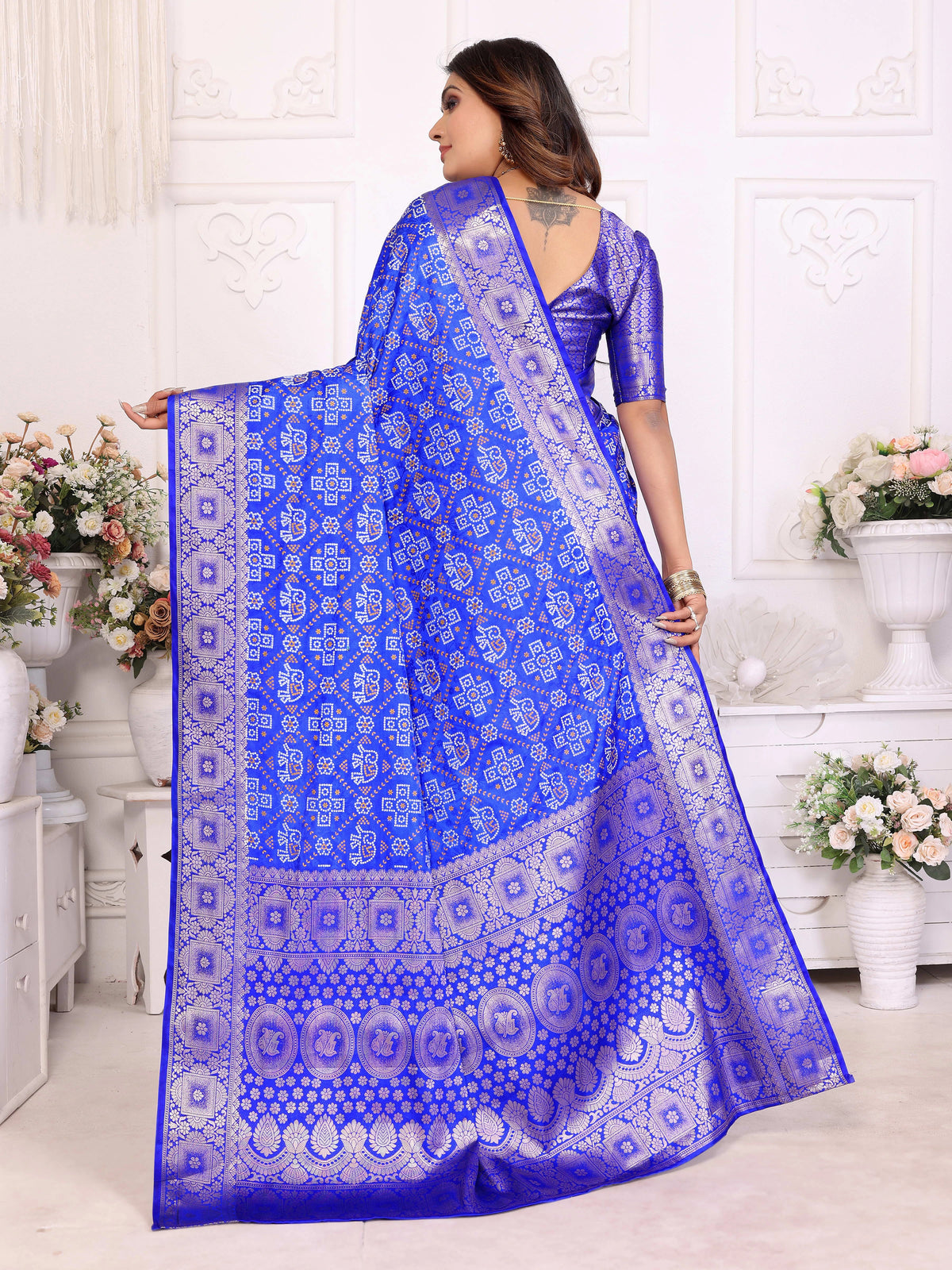 Woman wearing a blue saree with white patterns in a decorated room.