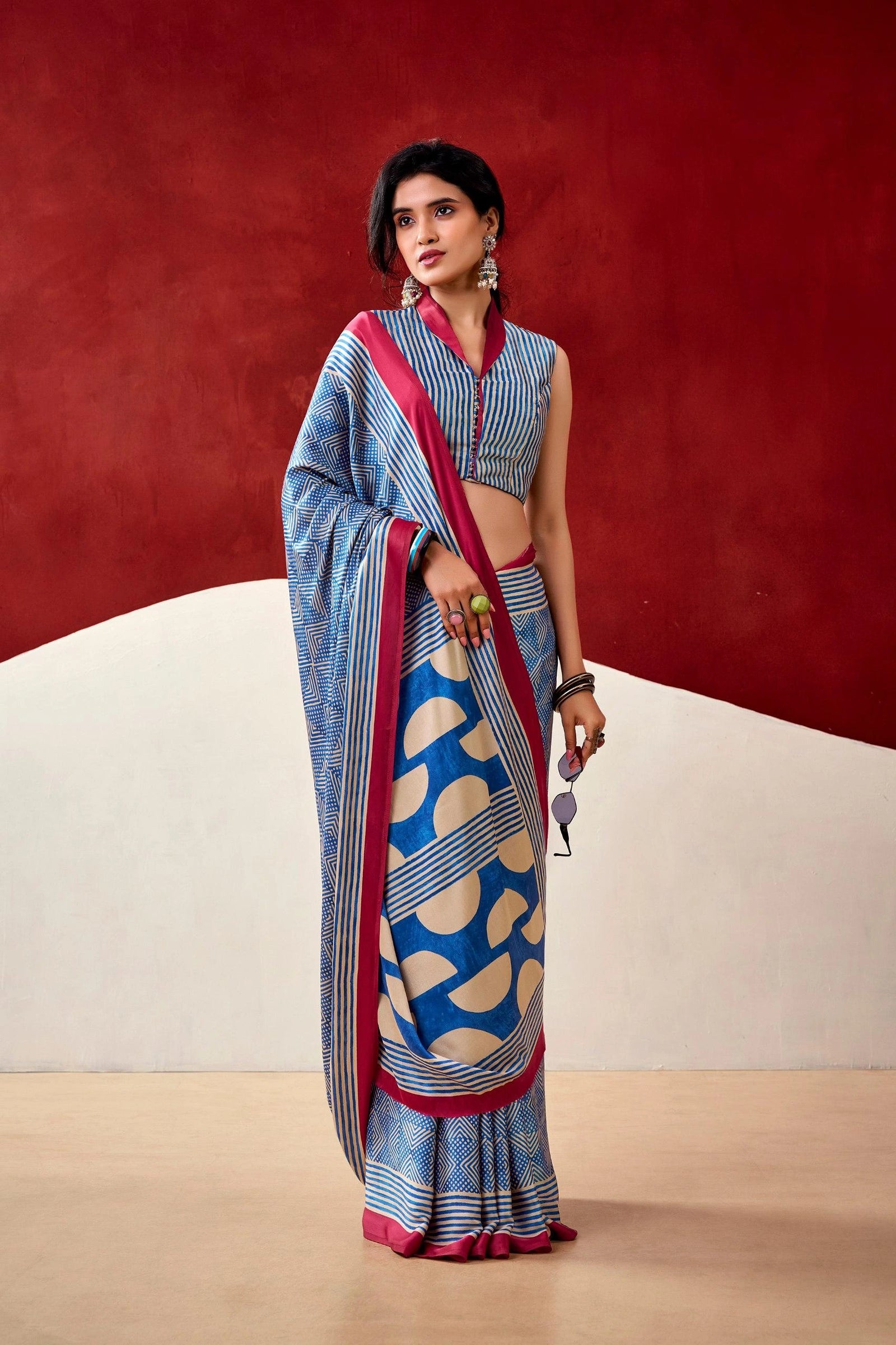Woman wearing a blue and red saree with a geometric pattern against a red background