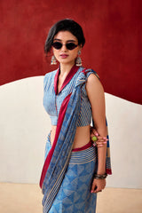 Woman wearing a blue and red saree with sunglasses against a red background
