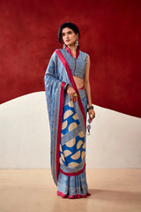 Woman wearing a blue and red saree with a geometric pattern against a red background